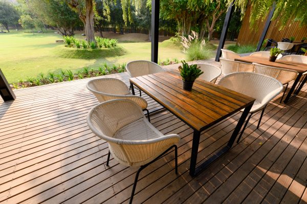 Wooden chair with table and green flora on patio at sunset